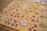 Mixed-texture weave with raised raspberry and ivory floral pile on a saffron flatweave base.