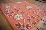 Close-up of the raised hand-knotted floral motifs against the flatweave cantaloupe field.