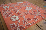 Raised ivory floral petals and raspberry stems on a cantaloupe reverse Soumac weave.