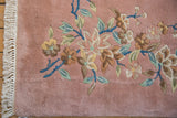 Plush dusty rose Japanese Art Deco rug, ornate floral vines in mint, sky blue, gold. White fringe.