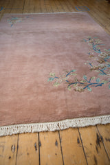 Plush dusty rose pile, green and blue ornate floral vines, and ivory fringe.