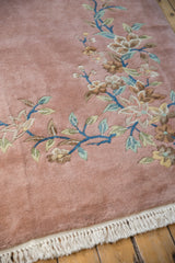Plush pile of Japanese Art Deco rug, dusty rose field with floral vines and fringe.