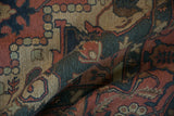 Textured pile of folded vintage Indian Serapi Soumac rug with madder red, dusty teal, and beige abrash.