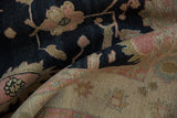 Close-up of serrated floral motifs in rose and sand on charcoal vintage Indian Soumac rug.