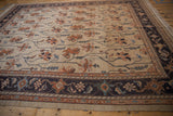 Intricate Serapi rug border featuring dusty navy blue, terracotta floral vinery on an ivory field.