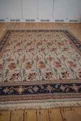 Classic Serapi rug: continuous floral vinery on ivory, dusty navy border, and fringe.