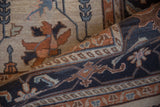 Curled hand-knotted Serapi rug, showing floral motifs in dusty navy, terracotta, and ivory.