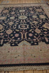 Vintage Sultanabad rug showing charcoal floral field, beige patterned border and natural fringe.
