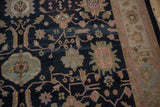 Charcoal Soumac rug detail with serrated florals, vinery, soft abrashes, and patterned beige border.