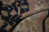 Folded vintage Sultanabad Soumac rug showcases abrash with charcoal navy, sand, and delicate floral vinery.