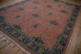 Vintage Indian Arts and Crafts carpet from an angle, highlighting its terracotta field and navy vinery.