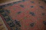 Angled view of a vintage Soumac rug's corner, featuring a navy border and terracotta vinery.