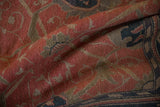 Soft folds showing the hand-woven texture of a vintage Soumac carpet in terracotta and navy.