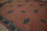 Moody, angled view of the vintage Arts and Crafts Soumac rug's terracotta and navy design.