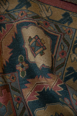 Close-up of hand-knotted pile in dusty teal, pale rose, and beige Soumac design.