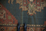 Abrashed dusty teal ground with serrated leaf and geometric floral border motifs.