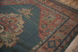 Serrated terracotta border with floral motifs on abrashed dusty teal vintage Serapi Soumac rug.