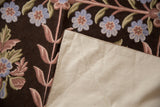 Vintage chainstitch rug with beige cotton canvas backing, revealing dark brown ground and dusty floral vines.