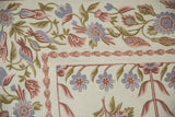 Vintage chainstitch rug corner with dusty rose, faded blue, olive floral vine pattern.