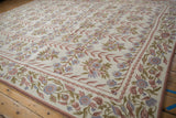 Ivory chainstitch carpet with traditional curvilinear floral vines in dusty rose, faded blue, and olive green.