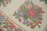 Curvilinear chainstitch floral bouquet in pastel pink, lavender, and sage green on ivory.