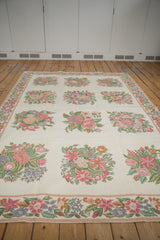 Intricate chainstitch border with curvilinear floral motifs in blush, green, and lavender.
