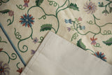 Curvilinear chainstitch pattern with green vines, pastel florals, ivory spiraling texture, and cotton backing.