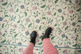 Vintage chainstitch rug close-up: ivory field, green, mauve, blue curvilinear floral pattern.