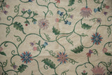 Detailed chainstitch weaving shows curvilinear dusty mauve, blue, green floral motifs on spiraled ivory.