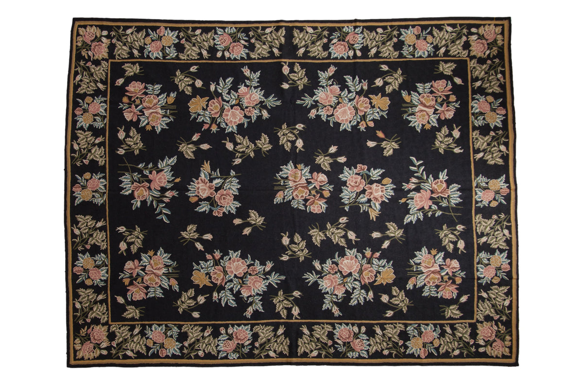 Vintage chainstitch carpet with blush and gold floral sprays on a navy blue field, framed by a matching floral border.