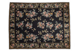 Vintage chainstitch carpet with blush and gold floral sprays on a navy blue field, framed by a matching floral border.