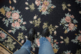 Detailed floral sprays in blush pink and green on a vintage navy blue chainstitch carpet.