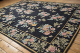 Corner view of a vintage chainstitch rug with a Colonial style floral border and dark navy field.
