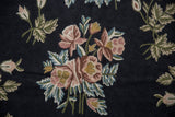 Detailed chainstitch weave of a floral bouquet in blush, raspberry, and green on the vintage carpet.