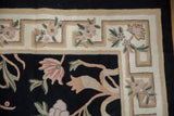 Chainstitch carpet corner: Arts and Crafts geometric border, black field, and dusty rose curvilinear florals.