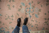 Vintage Arts and Crafts style chainstitch rug with rose ground and blue ribbon motif.