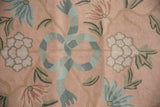 Blush chainstitch carpet detail with Arts and Crafts curvilinear florals and spiraling blue ribbon.