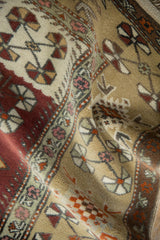 Soft folds showing the full hand-knotted pile and pinwheel blossoms on a vintage Melas rug.