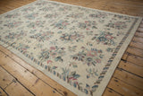 Vintage chainstitch carpet corner with repeating leaf border and soft floral motifs.