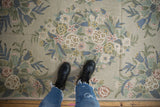 Vintage chainstitch rug detail: curvilinear floral pattern with spiraling texture in soft hues.