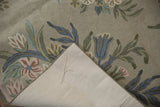 Corner of vintage chainstitch rug with curvilinear flowers, spiraling texture, and cotton canvas backing.