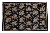 Vintage chainstitch carpet with pastel floral bouquets, scrolling vines, and a braided border on black, 6' x 9'.