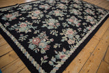 Chainstitch carpet detail highlighting pastel floral bouquets, leaves, and wavy border design.