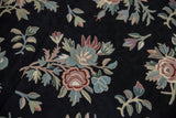 Vintage chainstitch rug detail with curvilinear floral sprays and scrolling tendrils in varied pastel tones on black.