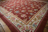 Curvilinear floral design and vines on the ivory border of a chainstitch carpet.