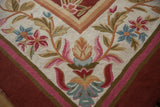 Chainstitch rug detail: spiraling curvilinear floral pattern in ivory, red, pink, and green.