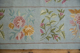 Powder blue chainstitch carpet featuring scrolling tendrils, dusty mauve and saffron floral motifs.
