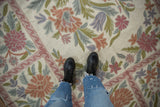 Vintage chainstitch carpet detail, showcasing curvilinear floral design in ivory, mauve, blue, and green.