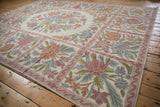 Textured chainstitch carpet detailing curvilinear floral motifs in pink, blue, and olive green.