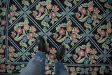 Vintage Chainstitch carpet's curvilinear floral pattern in pink, green, and dusty blue on black trellis.